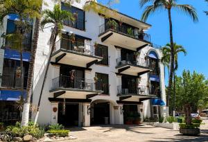 a white building with palm trees in front of it at Puerto de Luna Pet Friendly and Family Suites in Puerto Vallarta
