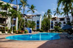 une piscine avec des palmiers en face d'un hôtel dans l'établissement Puerto de Luna Pet Friendly and Family Suites, à Puerto Vallarta