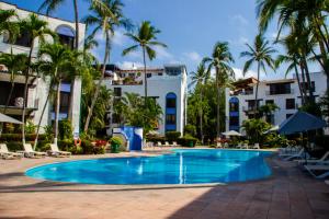 a swimming pool in front of a hotel with palm trees at Puerto de Luna Pet Friendly and Family Suites in Puerto Vallarta