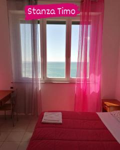 a bedroom with a bed and a window with pink curtains at Perla del Levante Hostel in Framura