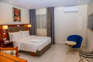 a hotel room with a bed and a blue chair at Geneva Hotel in Douala