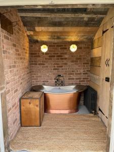 uma banheira num quarto com uma parede de tijolos em The Walled Garden at Cheshire Boutique Bathhouse em Nantwich