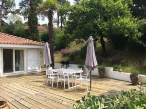 a patio with a table and chairs and an umbrella at BRUYERES - Capbreton, belle villa spacieuse entre ville et plages au calme in Capbreton