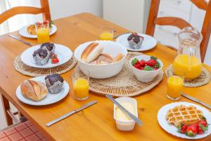 een tafel met borden ontbijtproducten en jus d'orange bij T - Casa Costa Doiro Guesthouse in Lagos