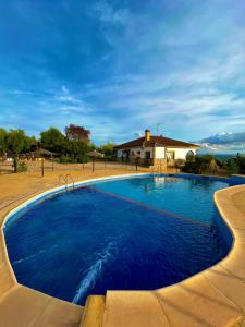 een groot blauw zwembad met een huis op de achtergrond bij Casa Rural Mirador de la Alcaidía in Hornachuelos