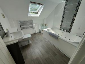a bathroom with a tub and a toilet and a sink at Pant Glas Barn in Llanbrynmair