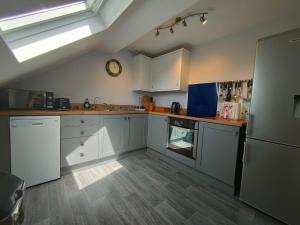 a kitchen with white cabinets and a clock on the wall at Pant Glas Barn in Llanbrynmair