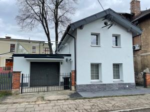 een wit huis met een zwarte garage bij Domek Przy Termach in Jelenia Góra