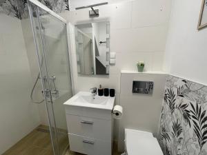 a white bathroom with a sink and a shower at Domek Przy Termach in Jelenia Góra
