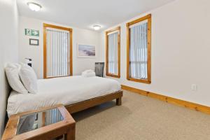 a bedroom with a large bed and windows at 3 Level Ski Chalet 7BR w Deck, Sauna & Ping-Pong! in Blue Mountains