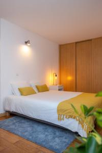 a bedroom with a large white bed with yellow pillows at Alta Guesthouse in Coimbra