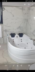 y baño con bañera blanca y paredes de mármol. en ELEGANT ROOMS - ULTRACENTRAL - jacuzzi cu hidromasaj, en Oradea