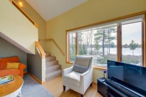 a living room with a large window and a white chair at Elk Rapids Condo with Balcony Overlooking Elk Lake! in Elk Rapids
