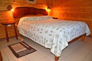 een slaapkamer met een bed in een houten kamer bij ABEDULES CABAÑAS PEHUENIA in Villa Pehuenia