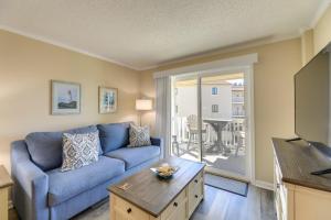 a living room with a blue couch and a table at Emerald Isle Vacation Rental with Resort Pool! in Emerald Isle