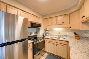 a kitchen with wooden cabinets and a stainless steel refrigerator at Emerald Isle Vacation Rental with Resort Pool! in Emerald Isle