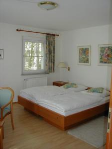 a bedroom with a bed and a chair and a window at Haus Waldfrieden in Bad Saarow