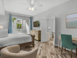 a bedroom with a bed and a desk and chairs at Blue Mountain Beach Condominium 102 by Newman-Dailey in Santa Rosa Beach