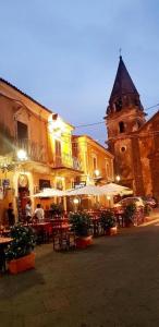 a street with tables and a building with a clock tower at Gli appartamenti del Casino dei Civili in Trecastagni