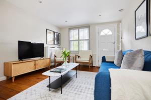 The Elmbridge Getaway - Glamorous 2BDR with Garden في لندن: غرفة معيشة مع أريكة زرقاء وتلفزيون