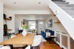The Elmbridge Getaway - Glamorous 2BDR with Garden في لندن: غرفة طعام وغرفة معيشة مع طاولة وكراسي