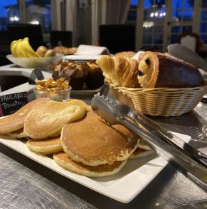 a plate of pancakes and bread on a table with a knife at Logis Hôtel Médiéval, Montélimar Nord in Rochemaure