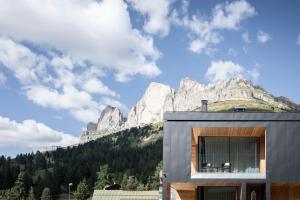 a house with a mountain in the background at Sport Hotel Passo Carezza in Vigo di Fassa