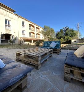 two beds and a wooden bench in front of a building at Logis Hôtel Médiéval, Montélimar Nord in Rochemaure