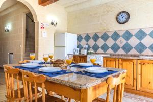 a kitchen with a large table with chairs and a clock at Ta Debora 3 bedroom Villa with private pool in Xagħra