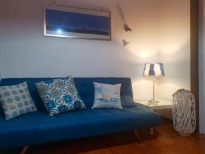 a blue couch with pillows in a living room at 2 bedrooms house at Letojanni 500 m away from the beach with sea view furnished terrace and wifi in Letojanni