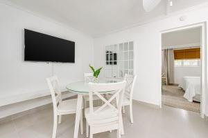 a white dining room with a table and chairs at The Palms Resort in Saint James