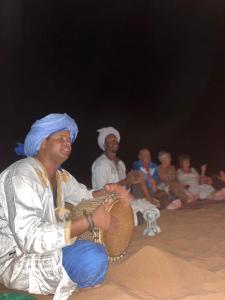 un groupe de personnes assises devant une foule dans l'établissement Rêves de désert, à M'Hamid El Ghizlane