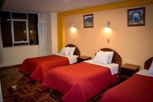 Habitación de hotel con 2 camas con sábanas rojas en Hostel Sol Andina Inn en Puno