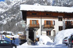 a building in the snow with cars parked in front at Hotel Flora Alpina in Gressoney-Saint-Jean