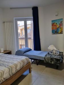 a bedroom with two beds and a window with a balcony at Kasamare apartments in Cefalù