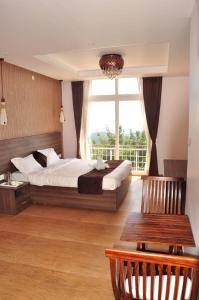 - une chambre avec un lit et une grande fenêtre dans l'établissement Vanam Holidays Inn, à Ooty
