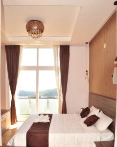 una camera da letto con un grande letto con una grande finestra di Vanam Holidays Inn a Ooty