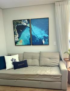 uma sala de estar com um sofá e três fotografias na parede em Apartamento Quartos Vista Praia do Morro Casais Melhor Localização, Super Completo 4 TVs Led, Camas-box Novas, 2 Quartos Suíte, Garagem, 2 Ar Condicionados, Wifi 300mb, Varanda Gourmet, Cervejeira, Novo para Famílias em Guarapari