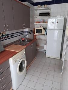 a kitchen with a white refrigerator and a washing machine at Piso Isla Cristina Punta del Caimán in Isla Cristina