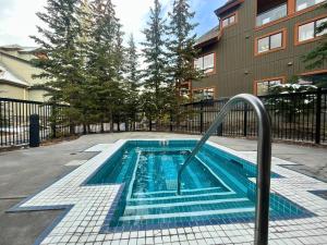 - une piscine avec un rail métallique à côté d'un bâtiment dans l'établissement Fenwick Vacation Rentals Suites with Pool & Hot tubs, à Canmore