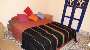 sypialnia z łóżkiem z kolorowymi poduszkami w obiekcie Taghart, la belle demeure w mieście As-Suwajra