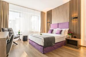 Habitación de hotel con cama morada y escritorio. en Unique Boutique, en Bucarest