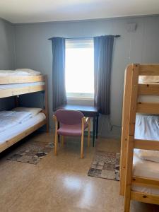 a room with two bunk beds and a chair and a window at Skoghus in Silsand