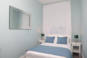 Dormitorio blanco con cama con almohadas azules en Dillon house, Ballina, en Ballina