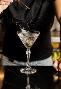 a person sprinkling a martini glass with a green olive at Hotel Mercure Roma Corso Trieste in Rome