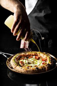 a person is cutting a pizza with a spatula at Hotel Mercure Roma Corso Trieste in Rome