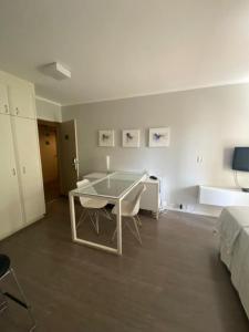 a white room with a table and chairs and a bed at Flat Avenida Paulista - Trianon in São Paulo