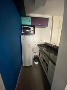 a small kitchen with a microwave and a refrigerator at Flat Avenida Paulista - Trianon in São Paulo