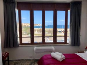 een slaapkamer met een raam met uitzicht op de oceaan bij Delos e Artemide in Siracusa