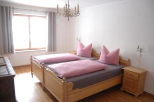 um quarto com 2 camas com almofadas cor-de-rosa e um lustre em Barrierefreie 3-Zi.-Ferienwohnung mit Gartenzugang in ruhiger, zentrumsnaher Lage em Oberammergau